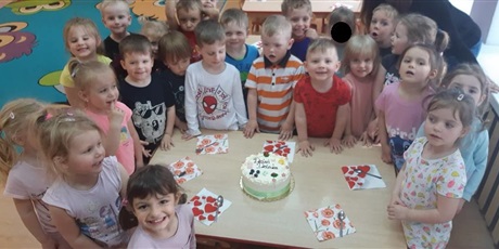 Powiększ grafikę: Na stole znajduje się tort. Wokół stołu stoją dzieci. Tort został przygotowany z okazji Dnia Dziecka.