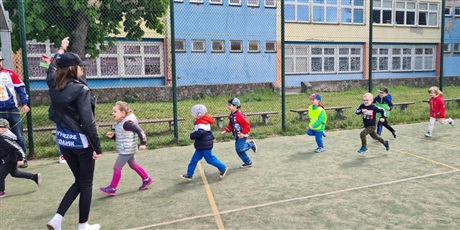 Powiększ grafikę: Dzieci biorą udział w biegu "Sprintem do maratonu". Kilkoro dzieci dobiega do linii mety. Zawody sportowe odbywają się na szkolnym boisku.
